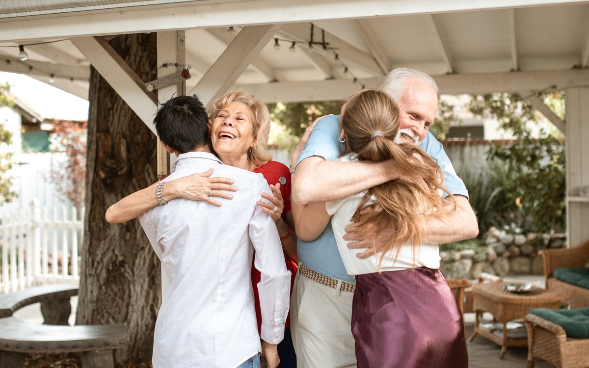 סבא וסבתא מתחבקים עם בני המשפחה בביקור משפחתי